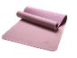 Light pink yoga mat partially rolled up on a black background