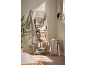 Green and grey towels on a wooden shelf, with a plant and bathroom accessories.