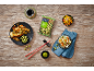 Asian food with chicken skewers, salads, and wasabi peanuts on a wooden table.