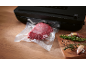 Black vacuum sealer with a vacuum-packed piece of meat and herbs.