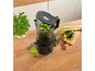 Black juicer on a wooden counter, making green juice from cucumbers and celery.