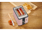 Pink toaster with toast, jam, and a knife on a wooden table.