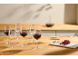 Red wine in glasses and a decanter on a wooden table with cheese and grapes.