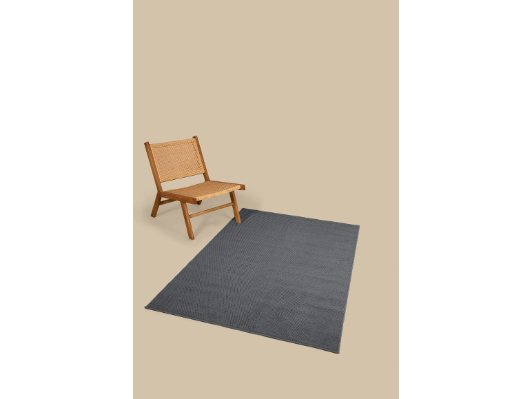 Wooden chair with woven seat and backrest on a gray rug.