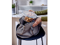 A person places a glass food container with roasted potatoes into a handbag.