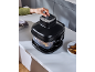 A person uses an air fryer on a kitchen counter, with potato wedges.