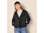 Woman in black pea coat, grey t-shirt, blue jeans, and black beanie.