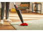 Person cleaning a rug with a steam mop in a living room.