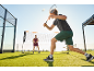 Man and woman playing badminton outdoors on a green lawn.