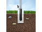 Flagpole with concrete ground anchor, grass, and blue sky.