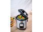 Stainless steel rice cooker with steamed vegetables on a wooden countertop.