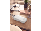 White power bank charging a pink smartphone and a laptop on a wooden table.