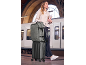 Woman with a backpack and a wheeled suitcase at a train station.