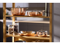 Copper pots and pans on wooden shelves in a kitchen.