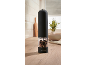 Electric pepper grinder with a transparent chamber filled with peppercorns, on a kitchen counter.