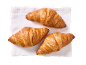 Three golden croissants on a white linen napkin.
