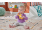 A baby sitting on a rug, playing with a yellow bear-shaped rattle.