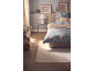 Bedroom with blue floral bedding, beige rug, and bedside table.