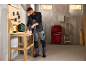 Man uses a drill at a wooden workbench in a workshop.