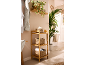 Bamboo bathroom shelf with baskets, towels, and plants in a bright bathroom.