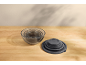 Set of glass mixing bowls with lids on a wooden table.
