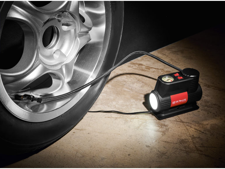 Portable tire inflator with a built-in light connected to a car tire.