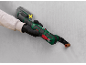 Handheld multi-tool with battery and blade cutting a copper pipe in a wall.