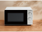 White microwave oven with a black door and a two-dial control panel, on a wooden table.