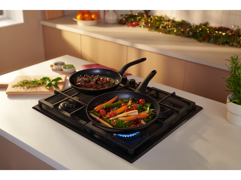 Two pans with Christmas dishes on a gas hob in a kitchen.