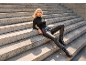 Woman in black leather pants and turtleneck sitting on stone steps.