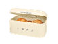 Cream-colored bread bin with an open lid, containing three round loaves of bread. The year '1973' is embossed on the front.