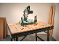 Miter saw and workbench with lumber against the wall.