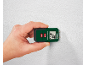 Hand holding a wood moisture meter against a white textured wall, displaying 28°C and 8.0%.