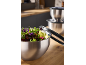 Stainless steel mixing bowls with fresh salad and kitchen tongs on a wooden counter.