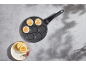 Pancake pan with smiling faces and finished pancakes with berries.