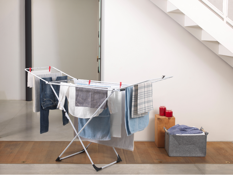 White clothes drying rack with clean laundry drying in a bright interior.