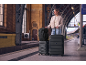 Woman with black luggage and backpack on a train platform.