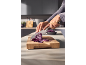 Hands slicing red cabbage on a wooden cutting board with a chef's knife.