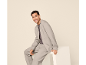 Man in a grey tracksuit sitting and smiling.