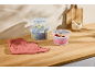 Plastic containers with blue lids filled with fresh food on a wooden countertop.