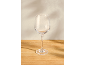 An empty wine glass on a wooden table with a light wall in the background.