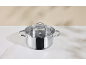 Stainless steel pot with a glass lid on a marble surface.
