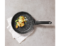Frying pan with potatoes and vegetables on a white cloth on a grey background.