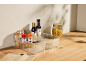 Transparent kitchen organizers with spices, legumes, oil, and pasta on a wooden countertop.
