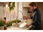 Man washing dishes in a kitchen decorated with Christmas garlands and a nutcracker.
