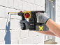Person drilling into a white brick wall with a cordless rotary hammer drill.