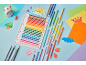 Colorful pencils and a notebook on a light blue background with paper cutouts.