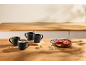 Black mugs with coffee and tea, and a raspberry tart on a wooden table.