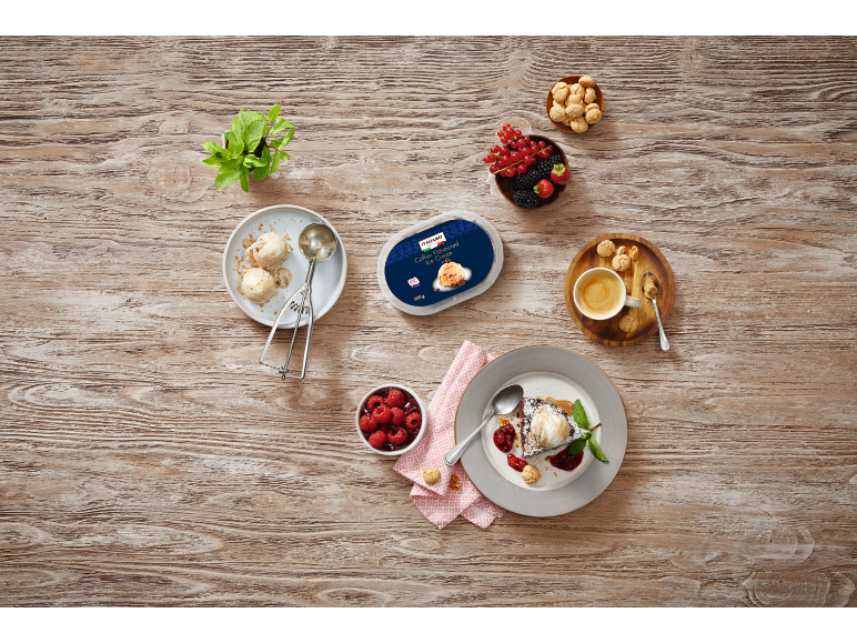 Coffee flavored ice cream with fruit and cookies on a wooden table.