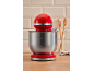 Red stand mixer with a stainless steel bowl in a modern kitchen setting.